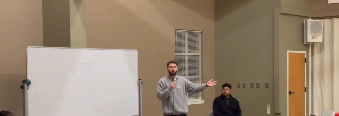 A speaker teaching a live group gathered in a meeting room